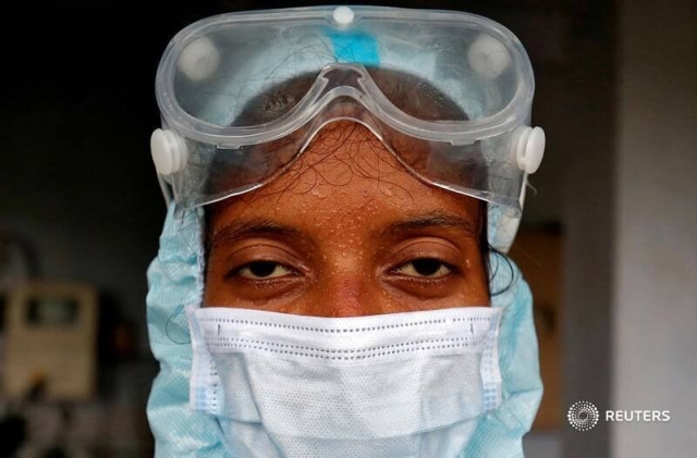 Beads of sweat run down the forehead of a healthcare worker wearing protective gear after she took swabs from residents for a rapid antigen test, amidst the coronavirus disease (COVID-19) outbreak, at a residential apartment in Ahmedabad, India, July 23, 2020. REUTERS/Amit Dave