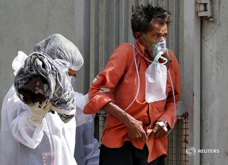 A patient with breathing problem is helped to walk towards an ambulance as he is being shifted to a hospital, amidst the spread of the coronavirus disease (COVID-19) in Ahmedabad, India, April 14, 2021. REUTERS/Amit Dave